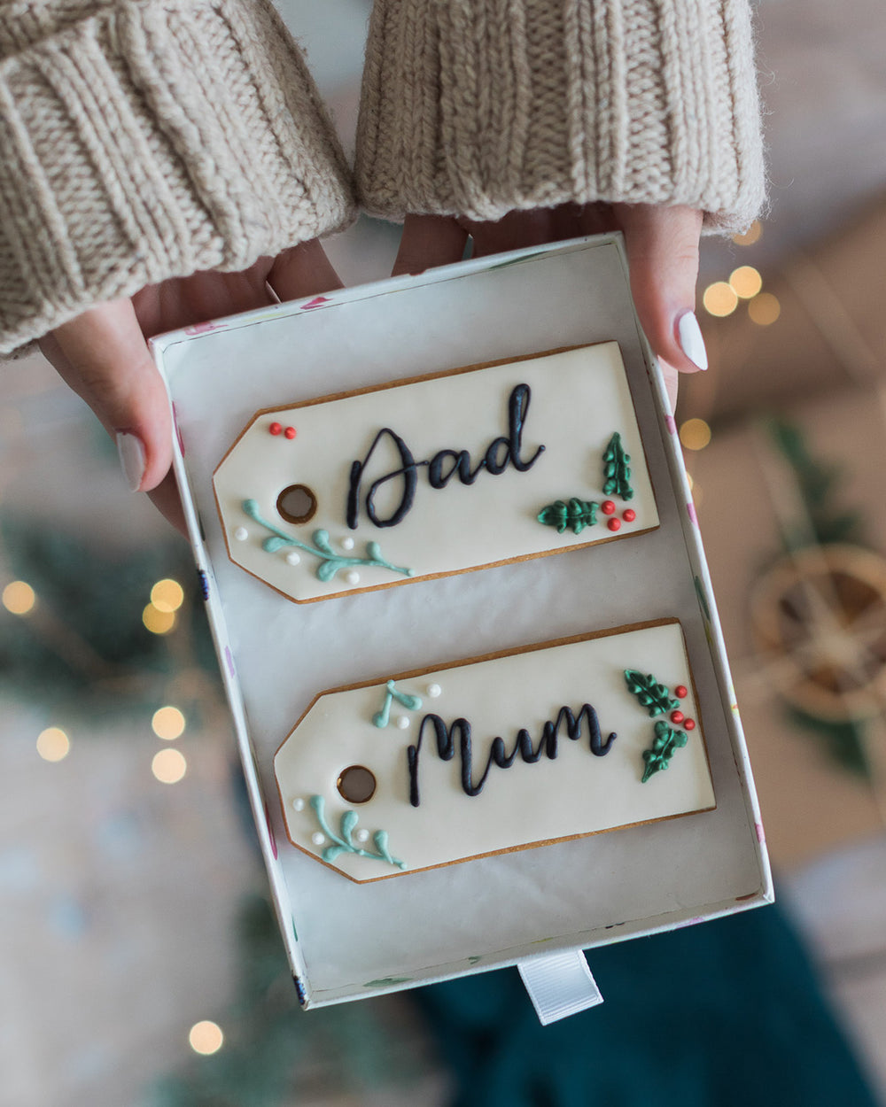 Honeywell Bakes Two Personalised Christmas Tag Biscuits - two Christmas themed decorated biscuits, held in a box with a blurred background