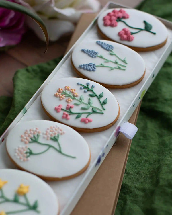 Honeywell Bakes Wildflower Biscuit Gift Set - Decorative cookies with floral designs in a box on a green surface.