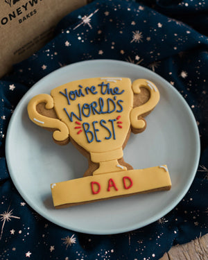 Honeywell Bakes You’re The World's Best - Personalised Trophy Biscuit - Cookie shaped like a trophy with 'You're the World's Best Dad' text on a blue plate.