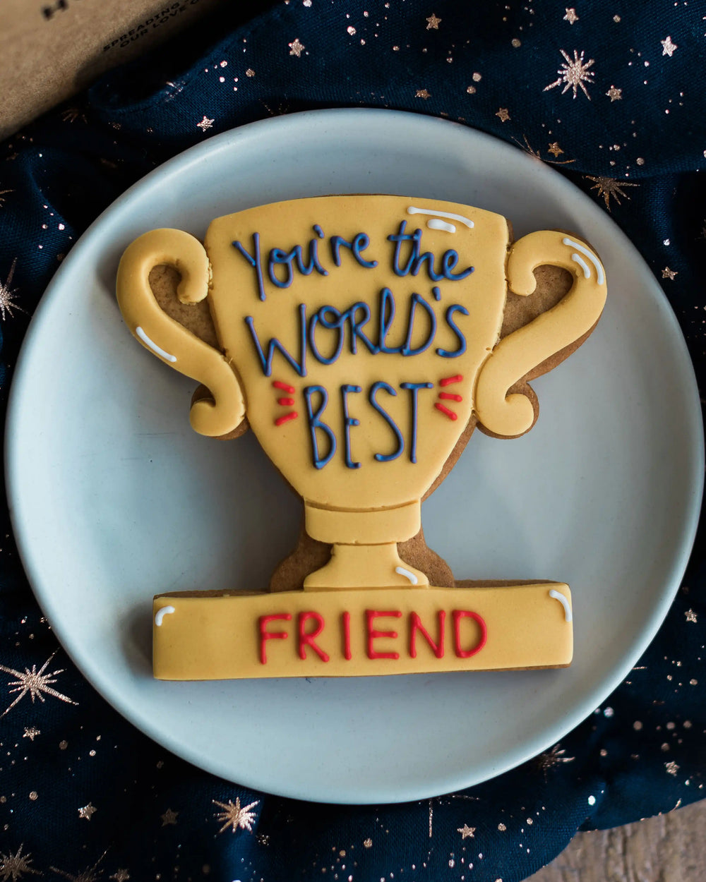 Honeywell Bakes You’re The World's Best - Personalised Trophy Biscuit - Cookie shaped like a trophy with 'You're the world's best grandad' text on a blue plate.