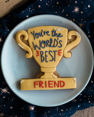 Honeywell Bakes You’re The World's Best - Personalised Trophy Biscuit - Cookie shaped like a trophy with 'You're the World's Best Friend' text on a blue plate.