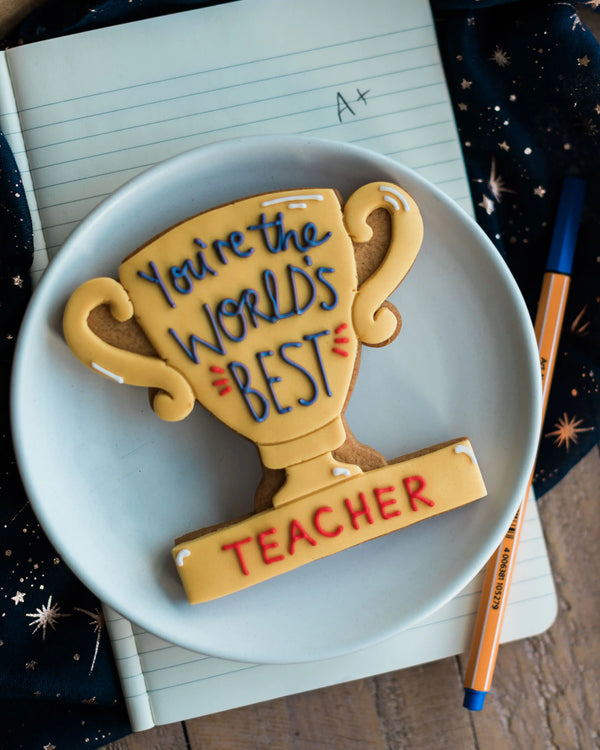 Honeywell Bakes You’re The World's Best - Personalised Trophy Biscuit - Cookie shaped like a trophy with 'You're the World's Best Teacher' text on a plate.