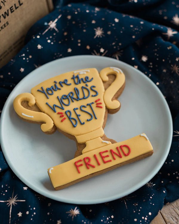 Honeywell Bakes You’re The World's Best - Personalised Trophy Biscuit - Cookie shaped like a trophy with 'You're the world's best friend' text on a blue plate.